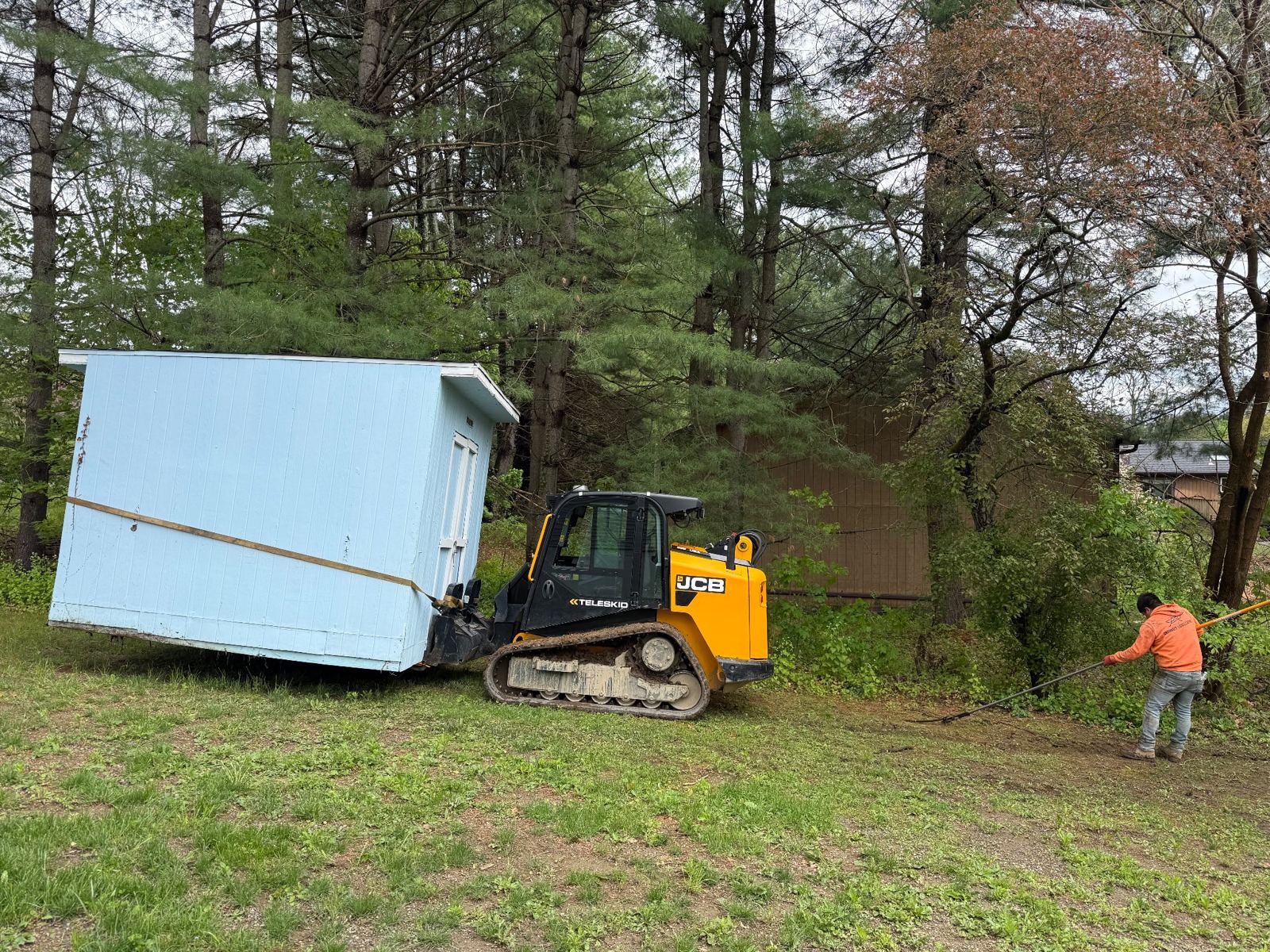 Compact track loader moving a shed
